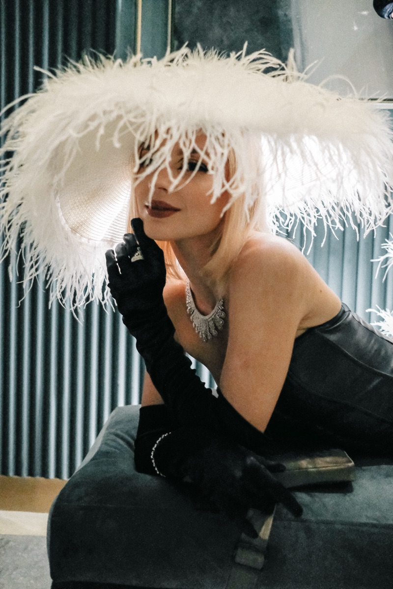 A performer in a white ostrich-feather hat, pearls and long black gloves