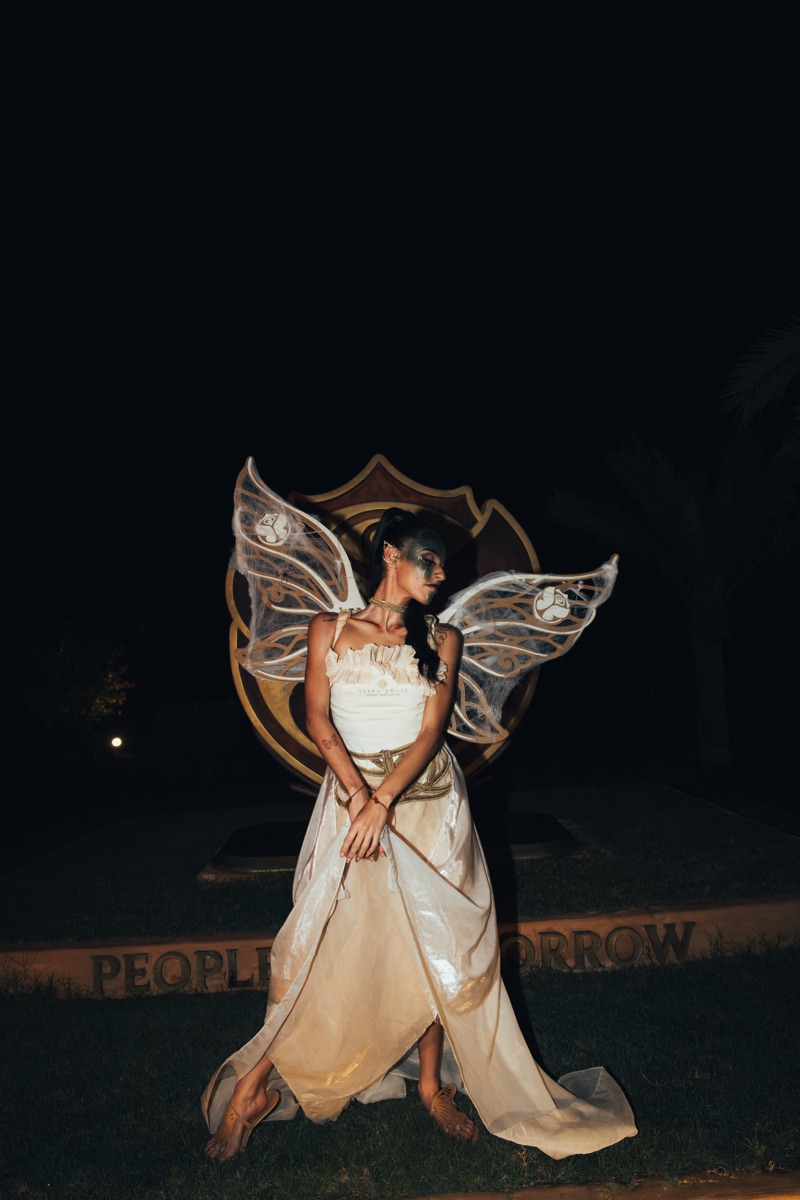 A fairy performer with translucent wings in an ivory gown at night