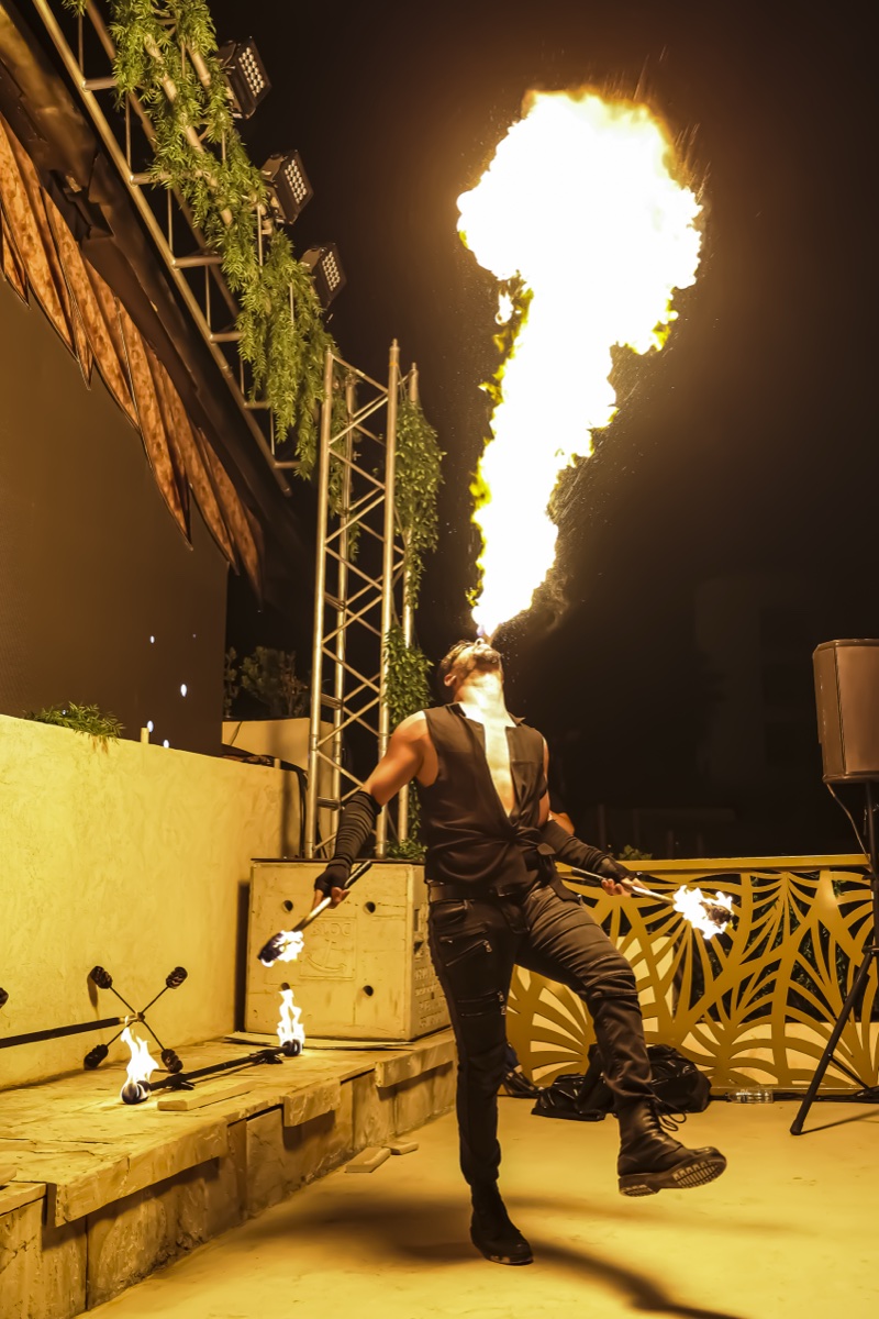 A fire-breather sending a column of flame into the night sky beside the stage truss