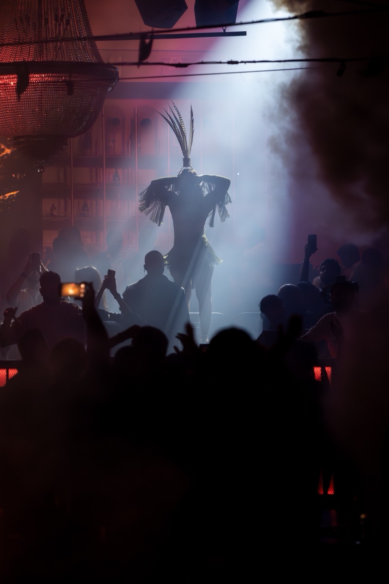 A performer with a towering feather headdress silhouetted above a crowd