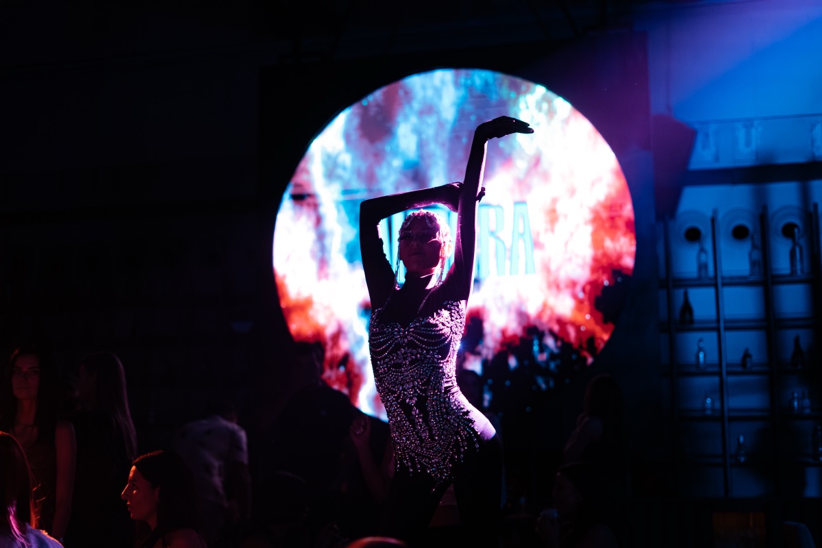 A dancer silhouetted before a circular screen of cosmic visuals