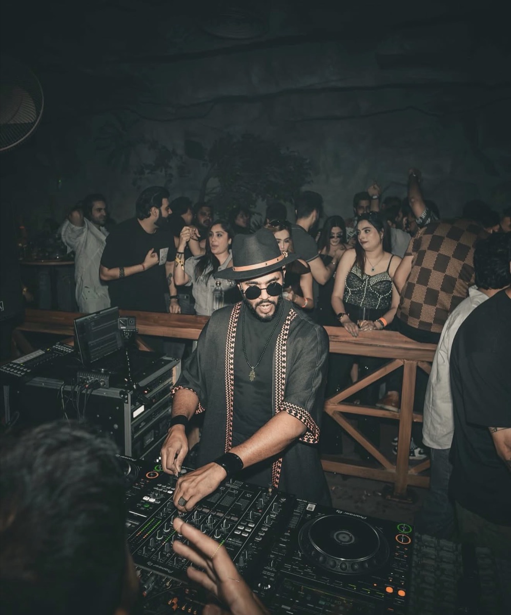 A DJ in a wide-brimmed hat playing to a full room