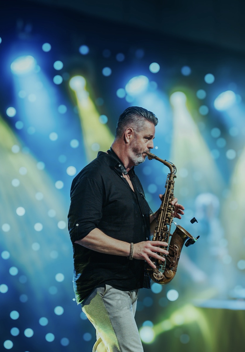 A saxophonist performing on stage under blue and gold lights