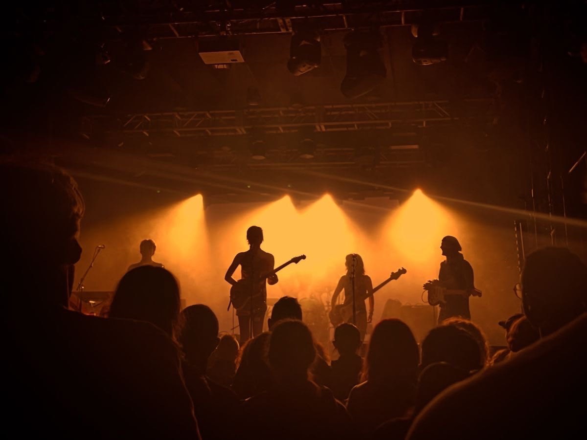 A live band silhouetted on stage in warm light above the crowd