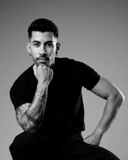 Alejandro, lead choreographer at Refined Performing Arts, seated on a stool in a black and white studio portrait