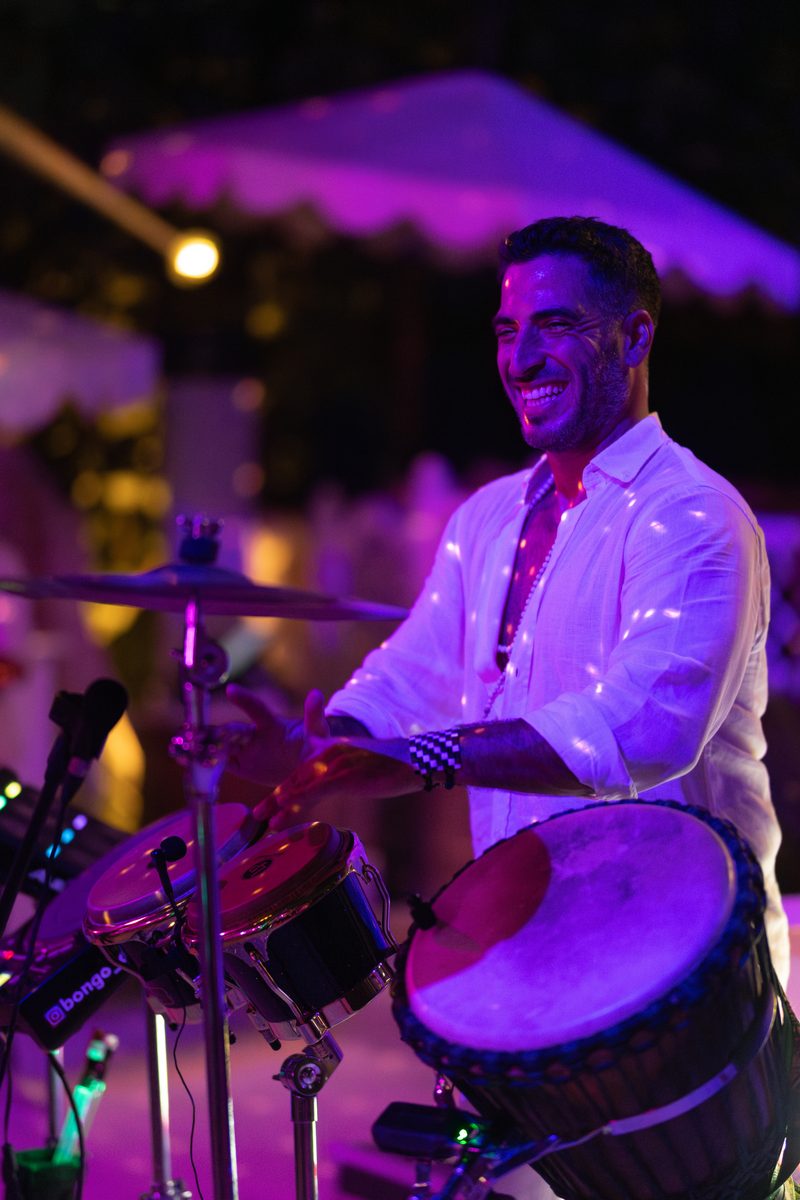 A percussionist performing on drums under violet event lighting