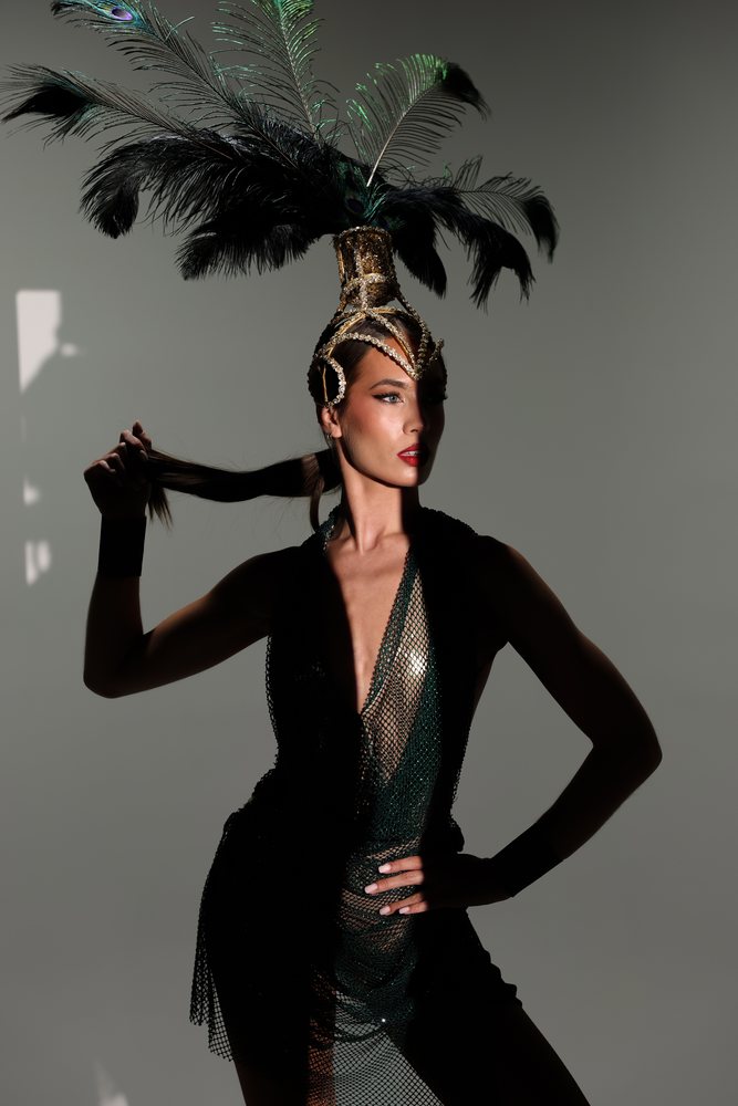 A performer in a navy corset and white feather headdress with long gloves