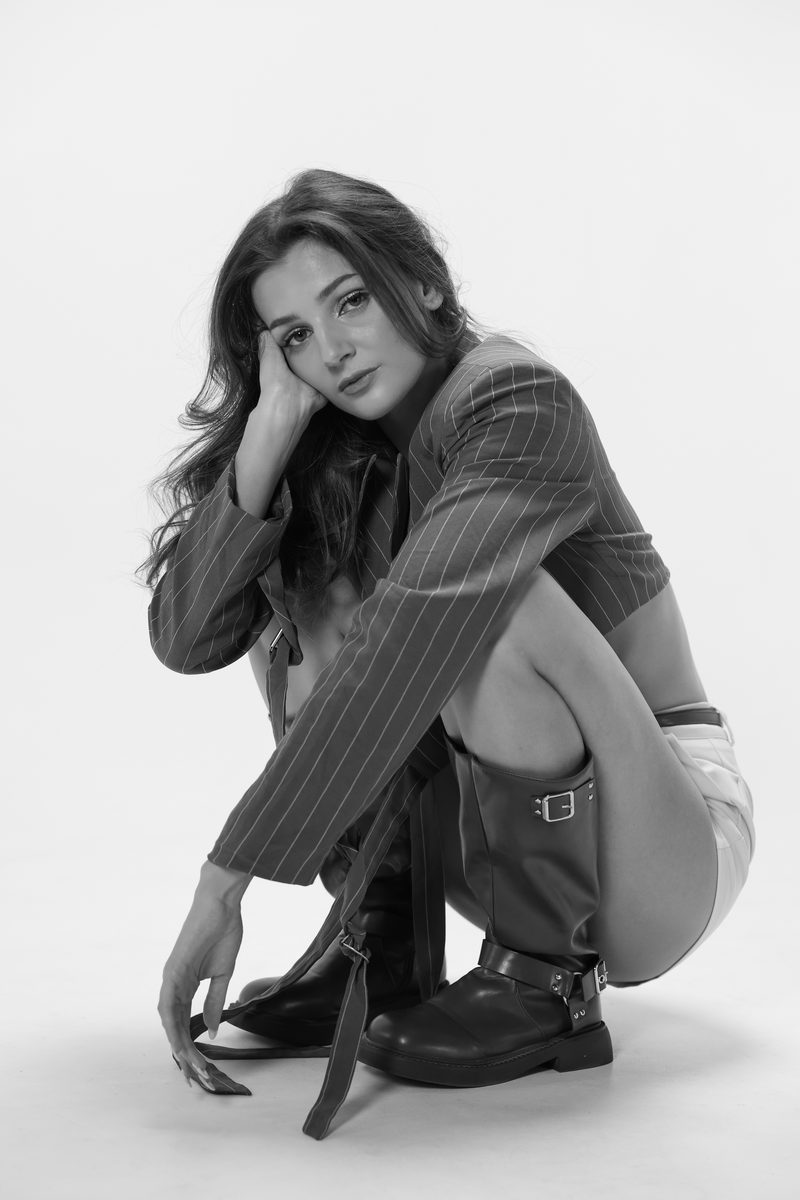 A dancer seated in a pinstriped jacket and boots